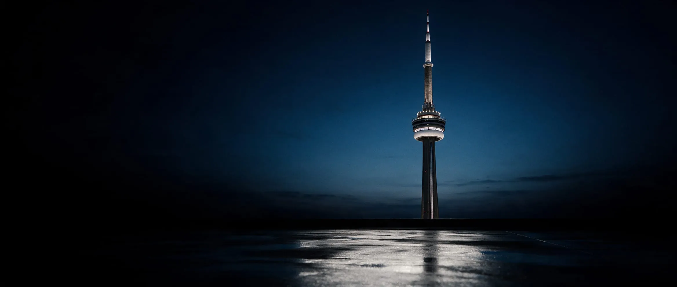 CN Tower at night over wet pavement